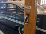 une voiture noire et blanche et une voiture verte dans un garage