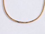 a close up of a gold necklace on a white surface