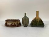 three different colored vases sitting next to each other on a white surface