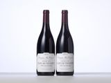 two bottles of red wine sitting on top of a table
