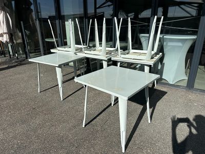 four white chairs and a table in front of a building