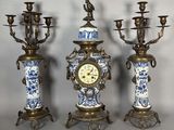 trois vases bleus et blancs sur lesquels est posée une horloge