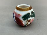 un petit vase orné d'un motif floral, posé sur une table