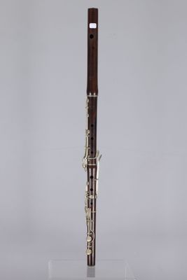 a silver and wood flute on a stand with a white background