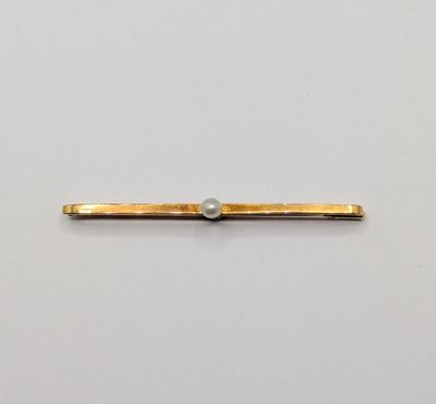 un gros plan sur un lingot d'or orné d'une perle