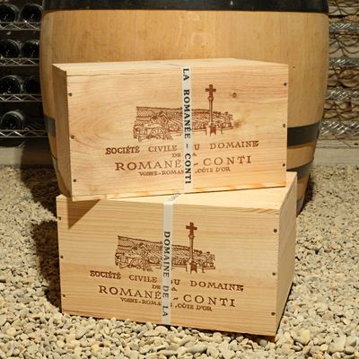 three wooden boxes stacked on top of each other in front of a barrel of wine
