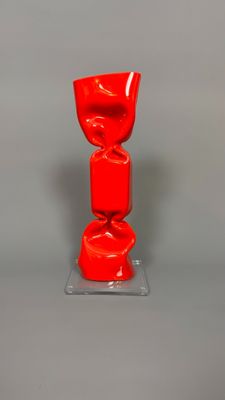 a red vase sitting on top of a clear base