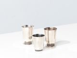 two silver cups sitting on top of a table next to each other