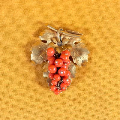 a brooch with red berries on it on a yellow cloth