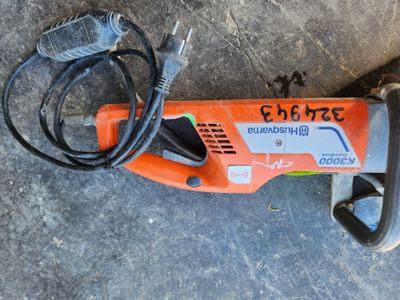 une perceuse électrique filaire posée par terre à côté d'un cordon d'alimentation