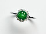 un gros plan d'une bague sertie d'un diamant vert sur une surface blanche