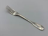 a silver fork on a white surface with a gray background