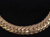a close up of a gold necklace on a black surface