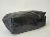 the large black leather bag is sitting on a white surface