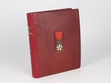 an old book with a red cover and a medal on it