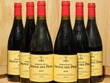 six bouteilles de vin rouge sont alignées sur un tonneau en bois