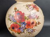 a vase with flowers painted on it sitting on a table