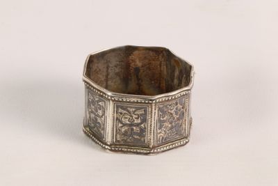 a silver ring with a design on it on a white surface