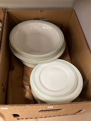 une boîte en carton remplie d'assiettes et de bols, posée par terre