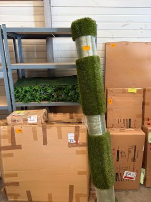 de nombreuses caisses remplies d'herbe verte posées par terre à côté d'un poteau