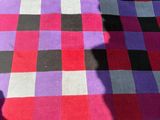purple and black checkered rug on the ground with a shadow of a person on it