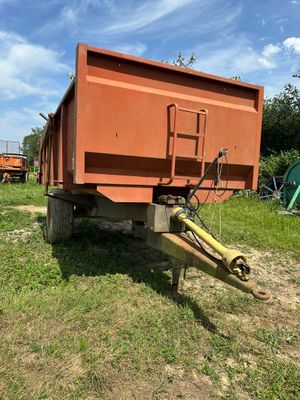 un camion-benne orange garé dans un champ à côté d'un tracteur vert