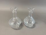 pair of clear glass vases sitting on top of a table