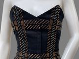 a mannequin wearing a black and gold dress with a gold belt