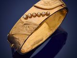 a close up of a gold bracelet on a blue background