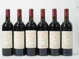 six bottles of wine are lined up in a row on a white surface