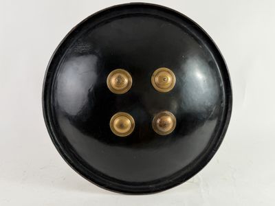un gros plan sur une assiette noire ornée de boutons dorés