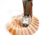 a watch sitting on top of a shell on a white surface