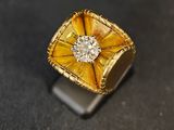 une bague jaune sertie d'un diamant, posée sur un fond noir