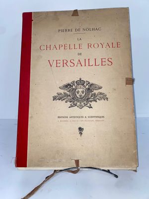 un vieux livre posé sur un support en bois, sur une surface blanche