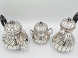 two silver teapots and a sugar shaker on a white background