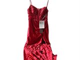 une robe rouge suspendue à un cintre devant un fond blanc
