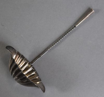 an antique silver spoon with a handle on a gray surface