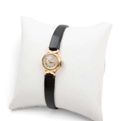 un gros plan d'une montre-bracelet posée sur un oreiller blanc