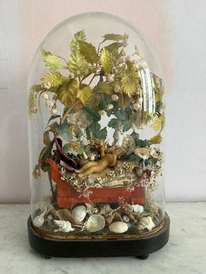 une cloche en verre posée sur une table, avec une figurine à l'intérieur