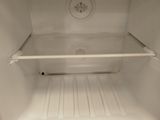 a small white refrigerator with its door open on the floor