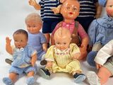 a lot of dolls that are sitting together on a white surface