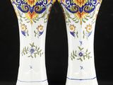 deux vases blancs ornés de motifs bleus et jaunes sur fond noir