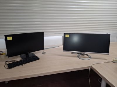 two computer monitors sitting on a desk in an office