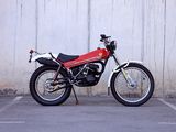 a red motorcycle parked in a parking lot next to a white wall
