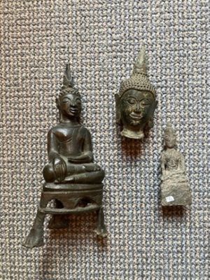 deux petites statues de Bouddha et une statue de Bouddha posée sur une table