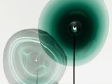 a green lamp that is on a stand next to a white wall