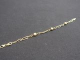 a close up of a gold chain bracelet on a black surface