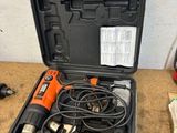 une perceuse électrique orange et noire dans un coffret posé sur une table