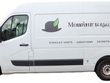 La camionnette est blanche, avec des finitions noires et un logo sur le côté.