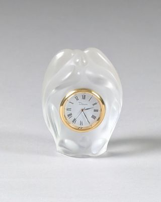 une petite horloge en verre posée sur une table blanche